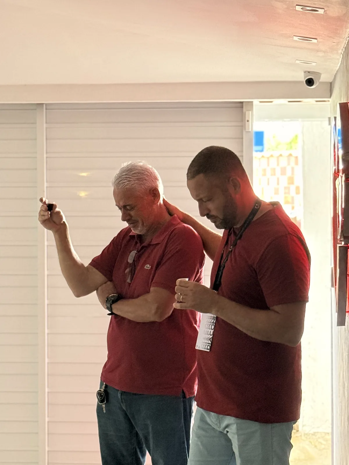 Dois obreiros de camisa vinho em oração, de cabeça baixa