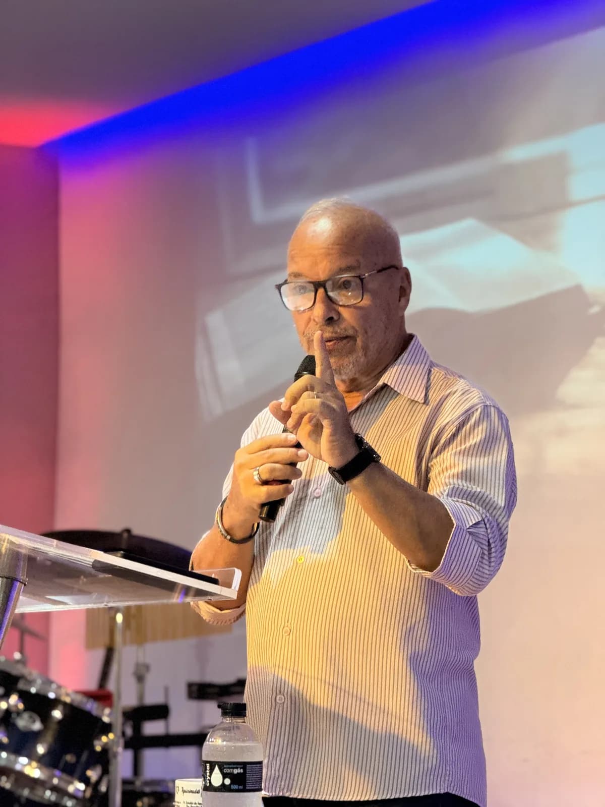 Pr. Jorge Teixeira pregando ao microfone atrás do púlpito