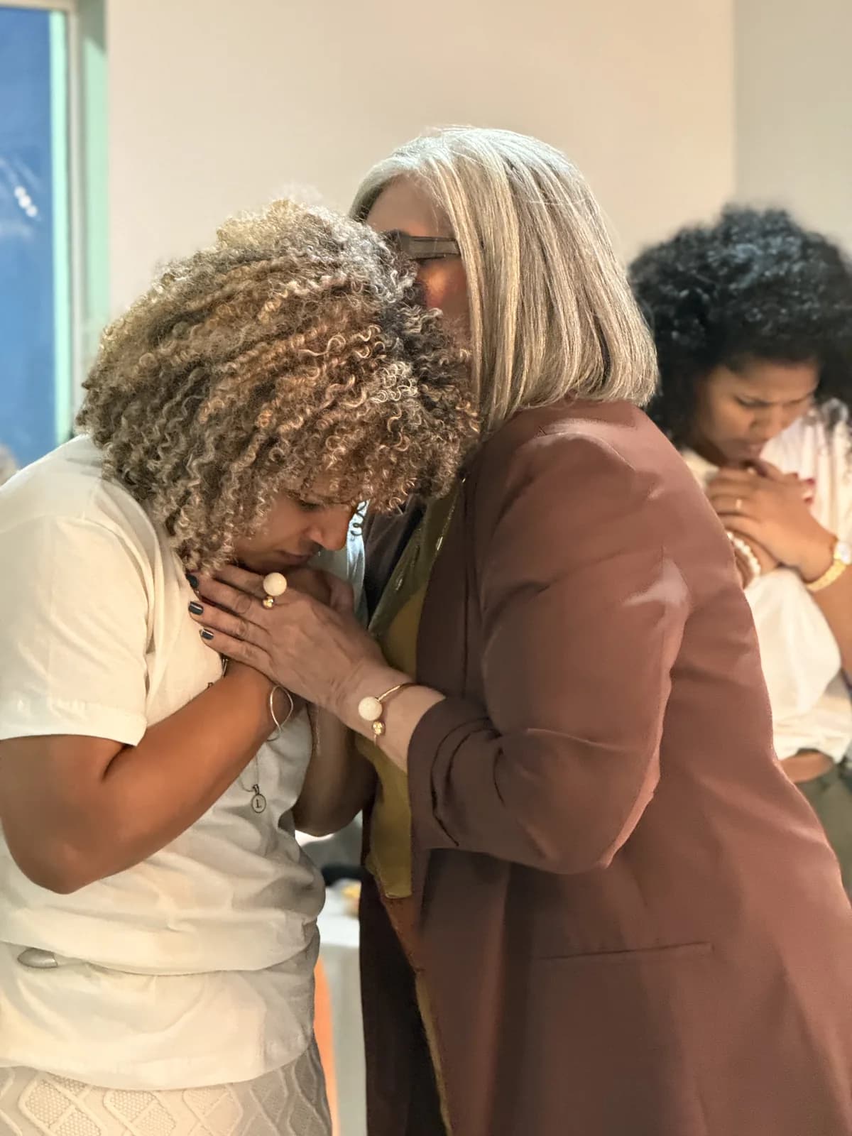 Duas mulheres abraçadas em oração durante a Pink Conference