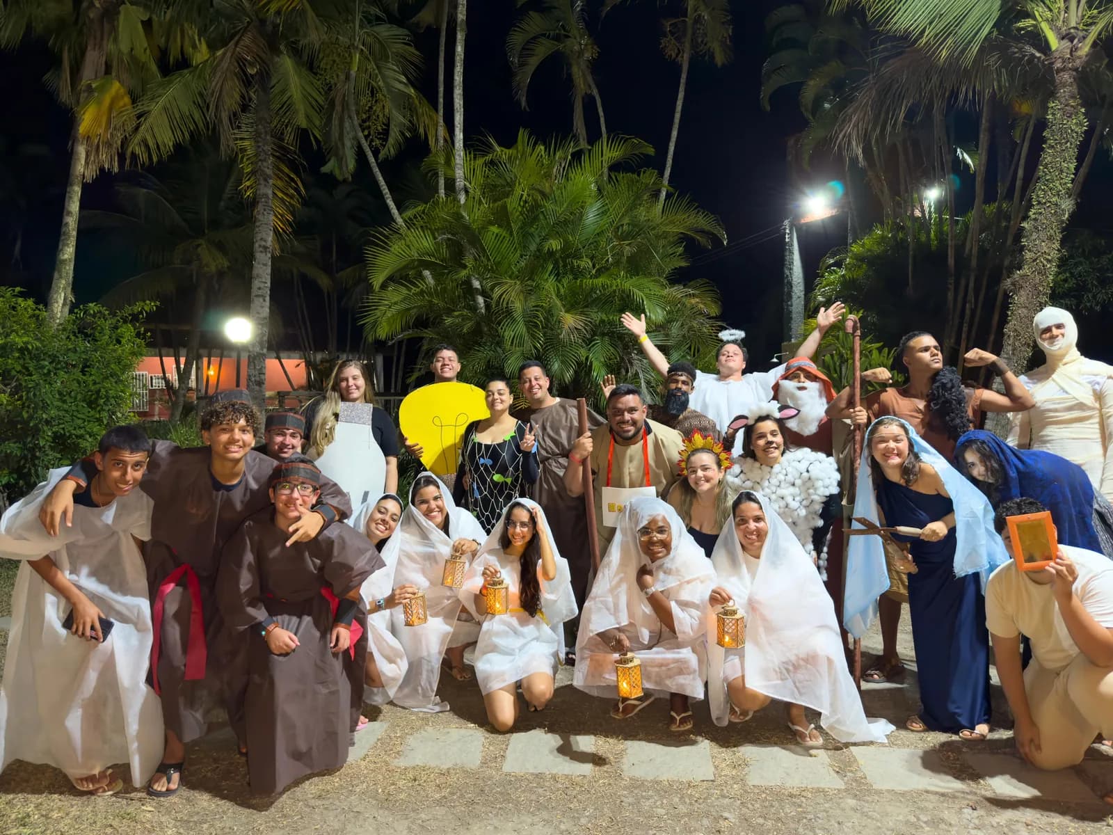 Turma do Retiro Huios reunida à noite entre coqueiros, em figurinos de encenação
